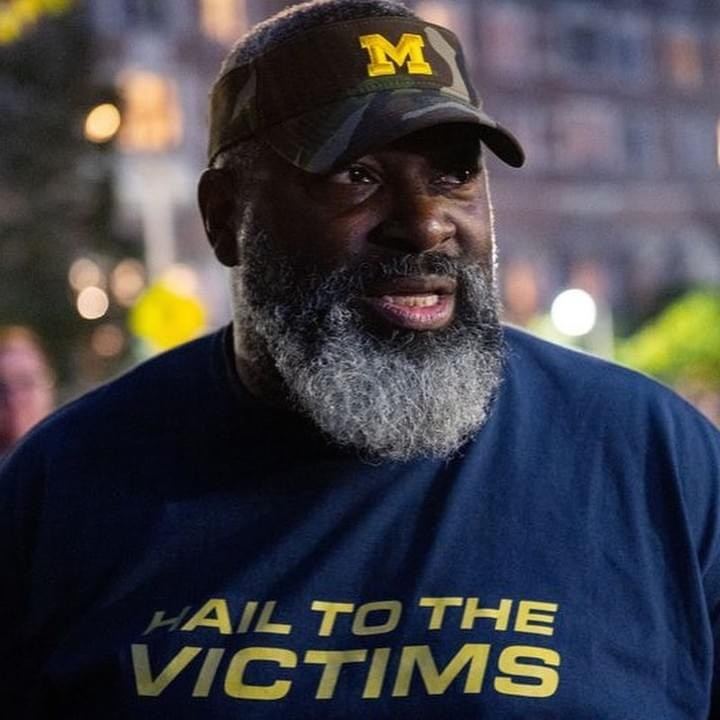 Jon Vaughn on campus at night, in a Michigan cap and a Hail to the Victims shirt.